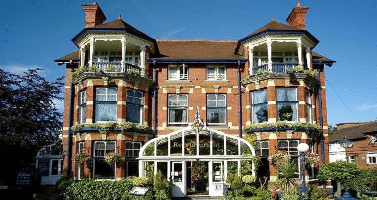 a large brick building with a greenhouse in front of it at Regency Hotel in Leicester