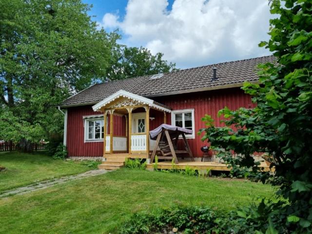 uma casa vermelha com um alpendre num quintal em Slättö 17 Lammhult em Lammhult