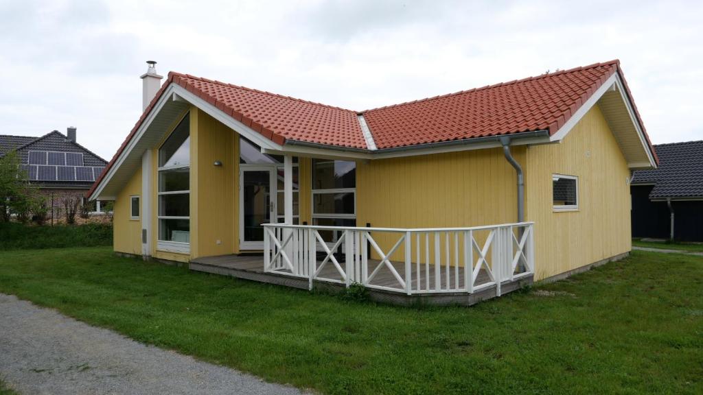 ein kleines gelbes Haus mit einer großen Terrasse in der Unterkunft Resort 2 Sea Lodge C 9 in Großenbrode
