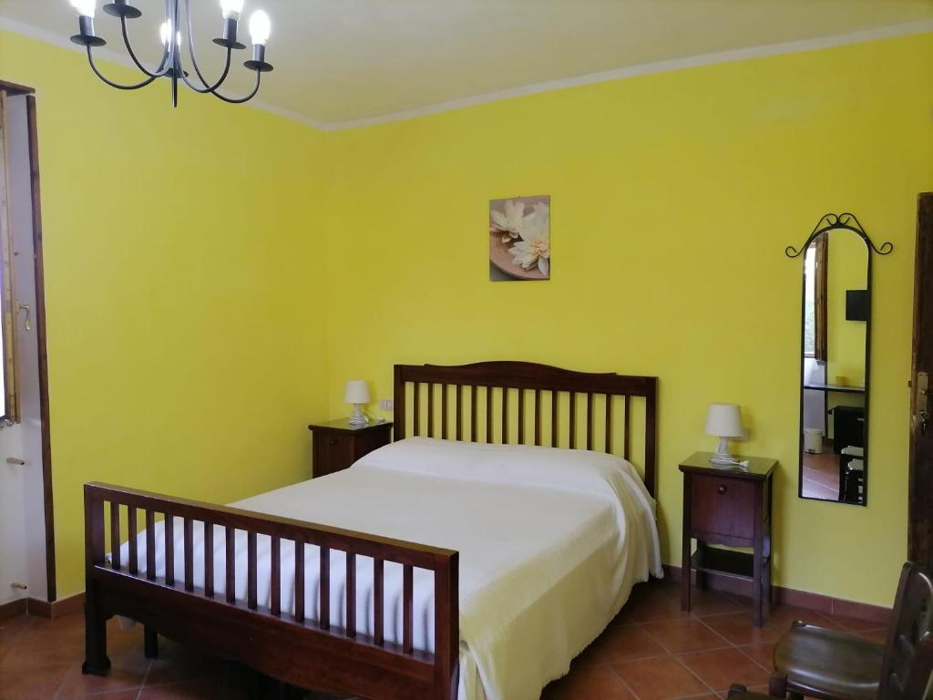 een slaapkamer met een bed met gele muren en een spiegel bij La Vecchia Casa in San Mauro Cilento
