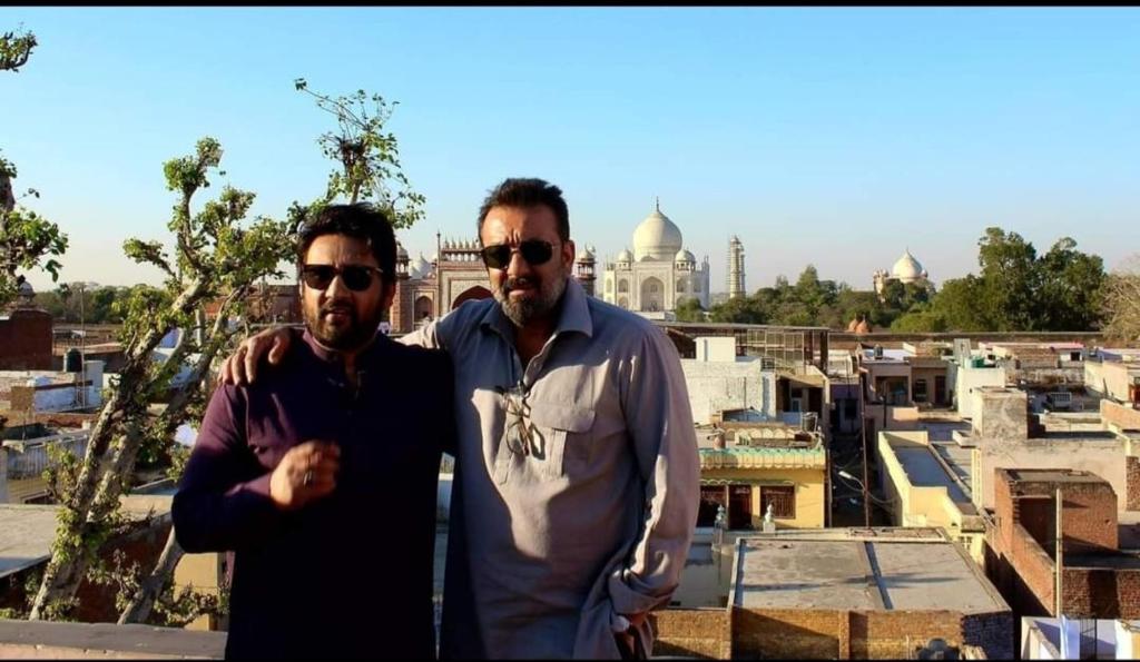 two men standing in front of a view of a city at Hotel Kamal Nearest To Taj Mahal in Agra