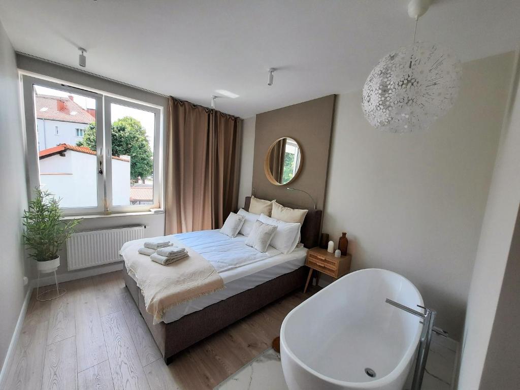 sypialnia z łóżkiem, wanną i umywalką w obiekcie PLUSK Apartments Mrągowo w mieście Mrągowo
