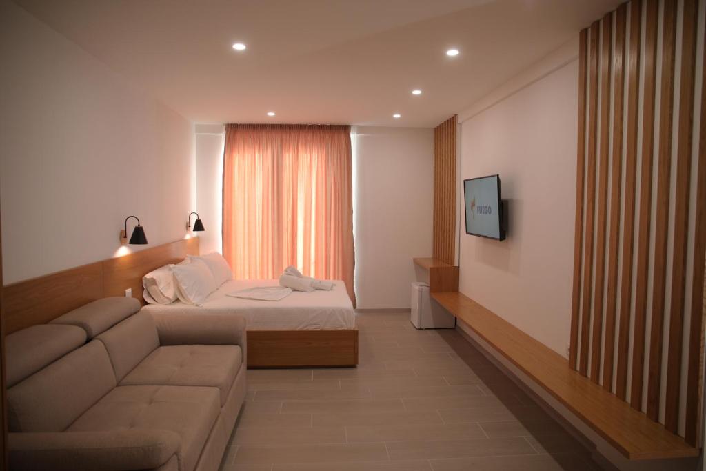 a bedroom with a bed and a couch and a television at Serenity In in Lezhë