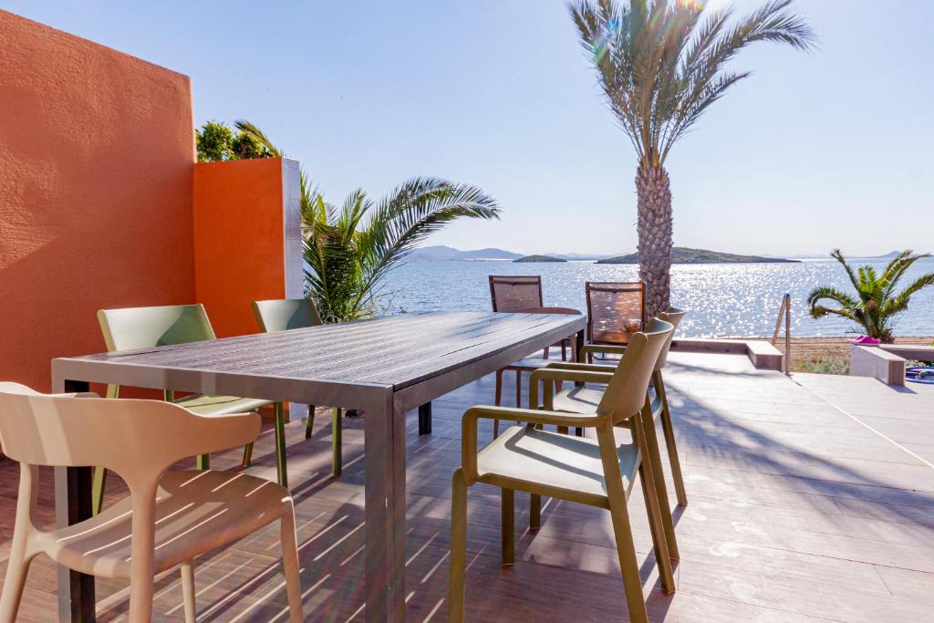 une table et des chaises en bois sur une terrasse avec de l'eau dans l'établissement Inmovecos Soling 11, à La Manga del Mar Meno