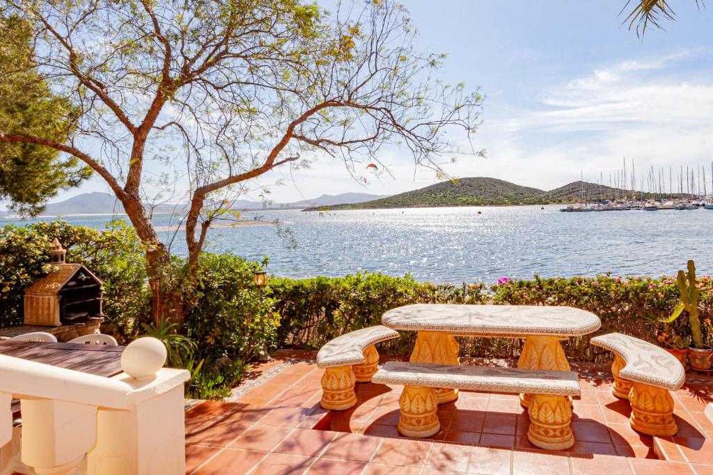 un patio avec une table et des bancs à côté de l'eau dans l'établissement Bahia de Las Palmeras 71, à La Manga del Mar Meno