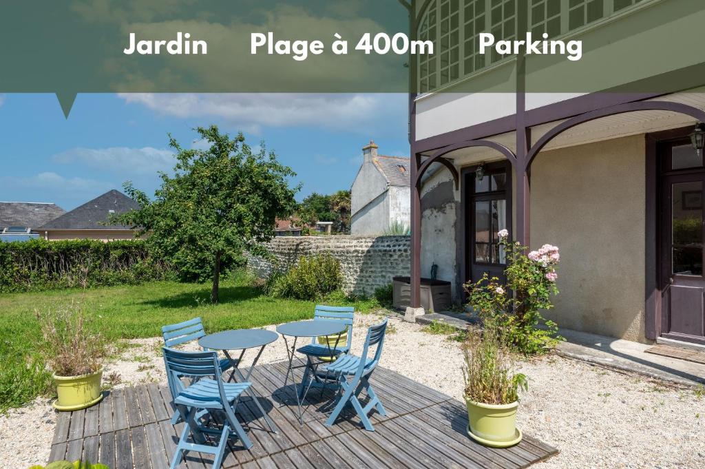 um pátio com uma mesa e cadeiras num quintal em Maison avec beau jardin - Centre ville d'Arromanches em Arromanches-les-Bains