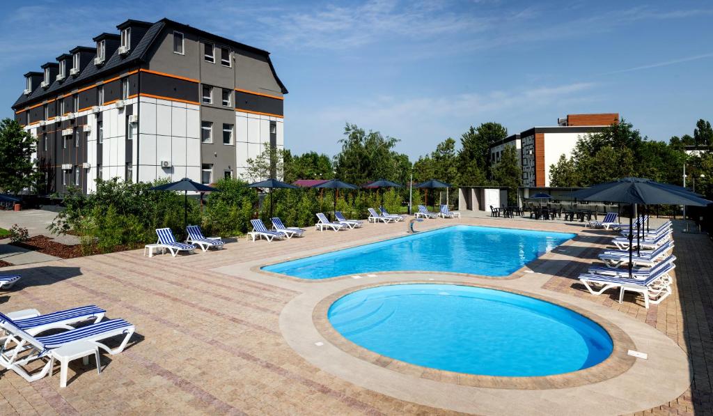a swimming pool with lounge chairs and a building at Аквамарин in Gribovka