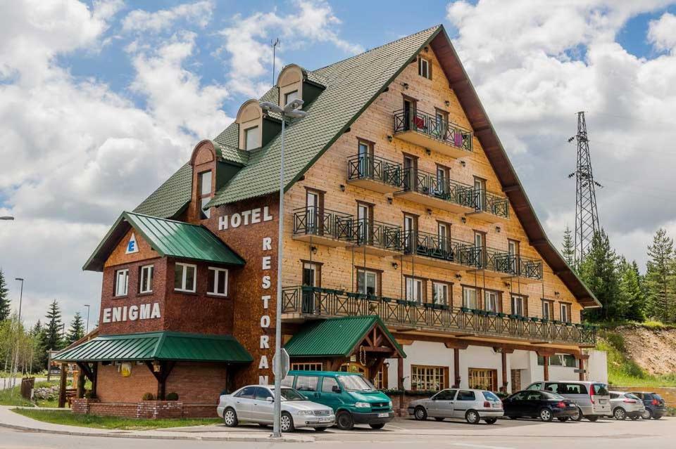 un gran edificio con coches estacionados frente a él en Hotel Enigma, en Žabljak