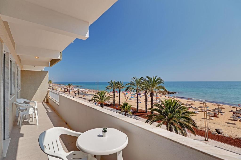 a balcony with a table and chairs and the beach at Quarteira Beach & Ocean View by Homing in Quarteira