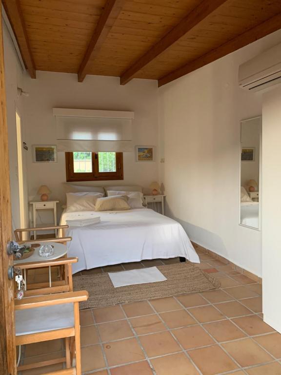 a bedroom with a white bed and a wooden ceiling at The Orange Grove Garden Room in Mytikas