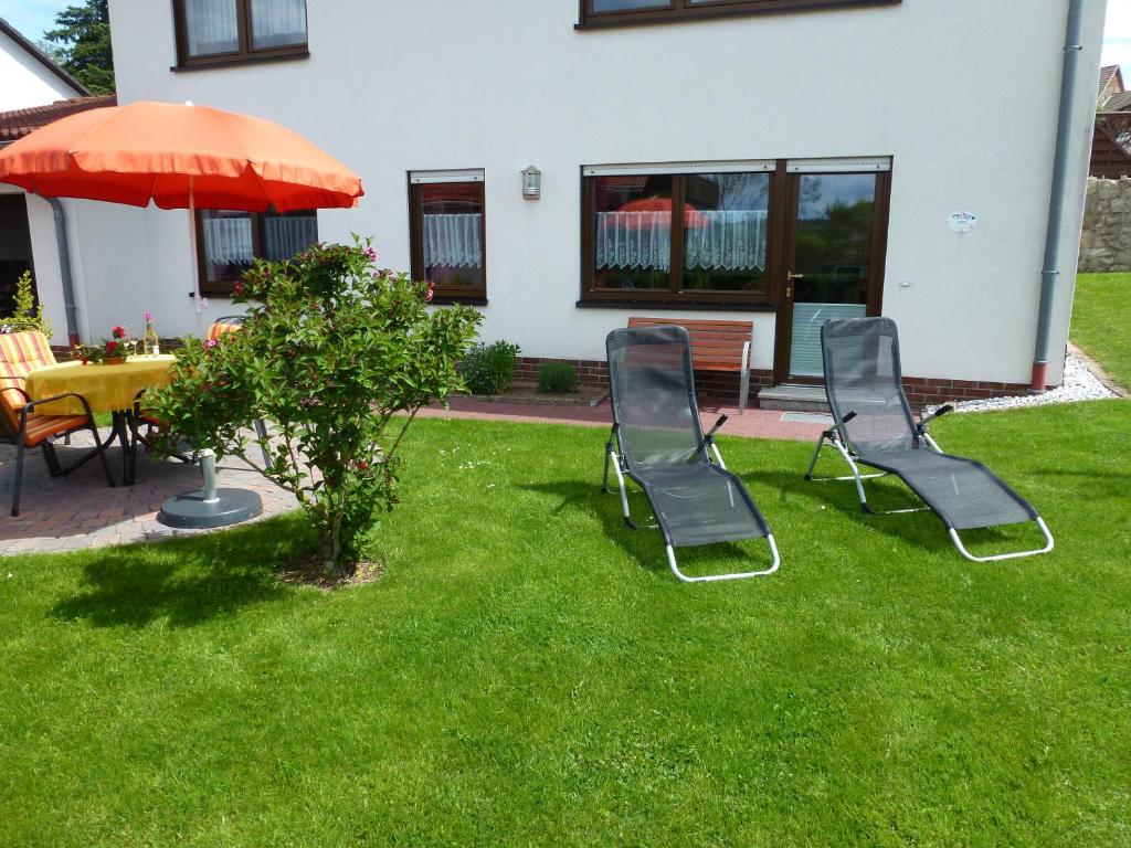 two chairs and a table and an umbrella in a yard at Ferienwohnung Sauerlandblick in Korbach