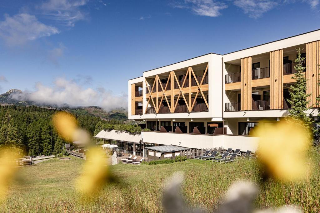 a building on a hill with chairs in front of it at Sporthotel Obereggen in Obereggen