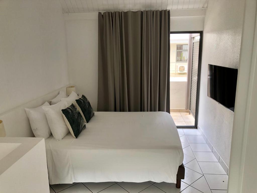 a white bed in a room with a window at Centr'Hotel in Marigot