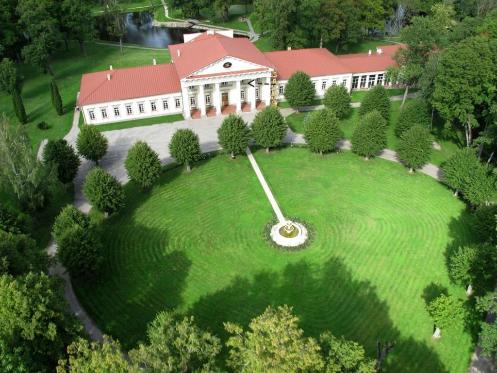 an aerial view of a large house with a large clock on a lawn at Taujėnų dvaro svečių namai in Towiany