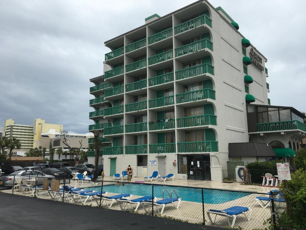 a hotel with a swimming pool in front of a building at Quail Inn and Suites - Myrtle Beach in Myrtle Beach