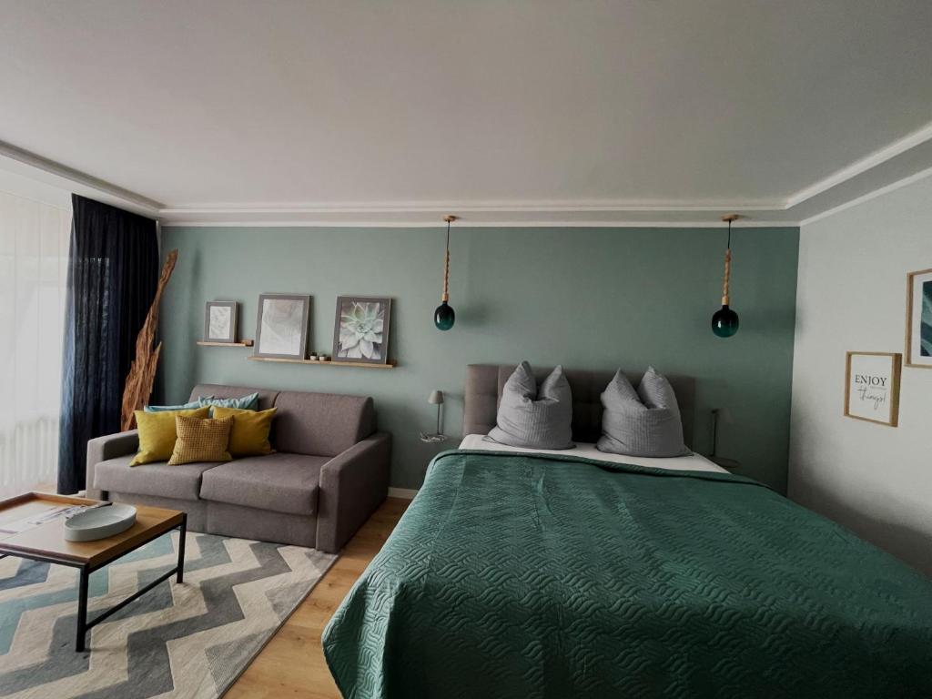 een slaapkamer met een groen bed en een bank bij Haus Vier Jahreszeiten am See Vier Jahreszeiten - HS 221 in Goslar