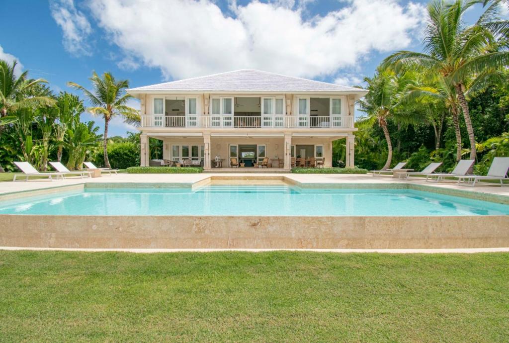 a house with a swimming pool in front of a house at Golf-front villa with large spaces, staff and pool, situated in luxury beach resort in Punta Cana