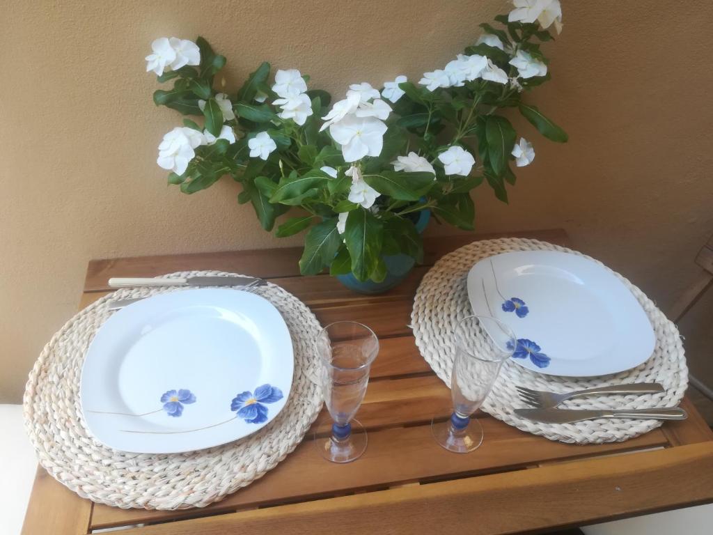 a table with two plates and a vase with flowers at Camera romantica nel carugio in Riomaggiore