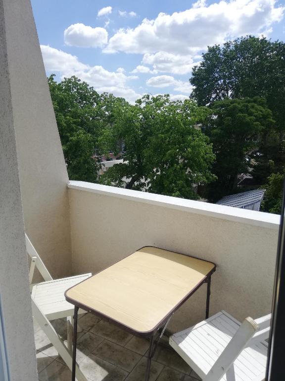 une table et des chaises sur un balcon avec une fenêtre dans l'établissement Quiet apartment, 12 mn from Paris, à Colombes