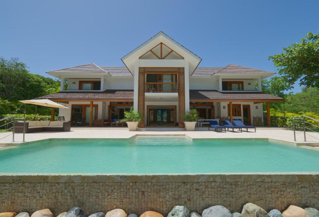 a house with a swimming pool in front of a house at Amazing 4-bedroom tropical villa with private pool and golf course view at luxury resort in Punta Cana
