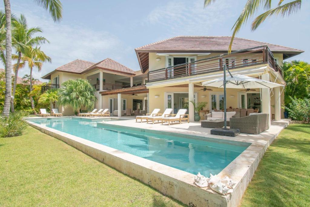 una casa con piscina frente a una casa en Spacious lake front villa with in-room jacuzzis in luxury golf and beach resort, en Punta Cana