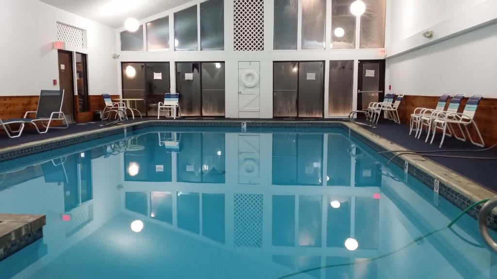 uma grande piscina com cadeiras e mesas num edifício em Cascades Lodge em Killington