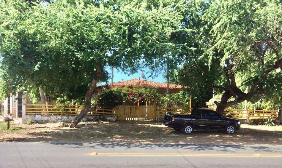 un camion noir garé devant une maison sous les arbres dans l'établissement Casa de praia rústica, à Luis Correia