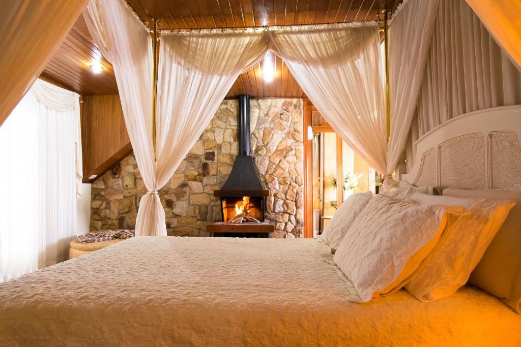 a bedroom with a bed with a fireplace in it at Pousada D'lines in Campos do Jordão