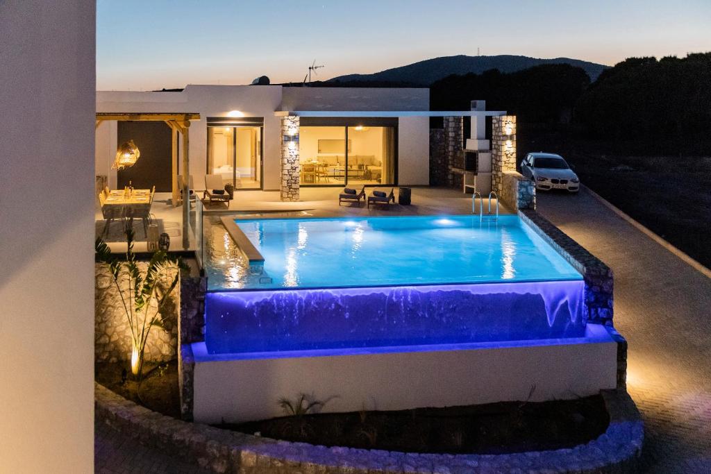 a swimming pool in front of a house at Grand Blue Villas Lachania in Lakhania