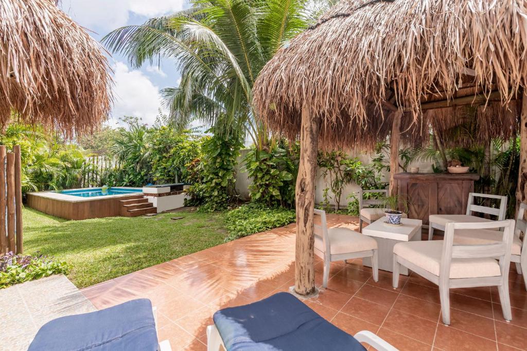 un patio con sillas, una sombrilla y una piscina en Casa Nona Azul, en Cancún