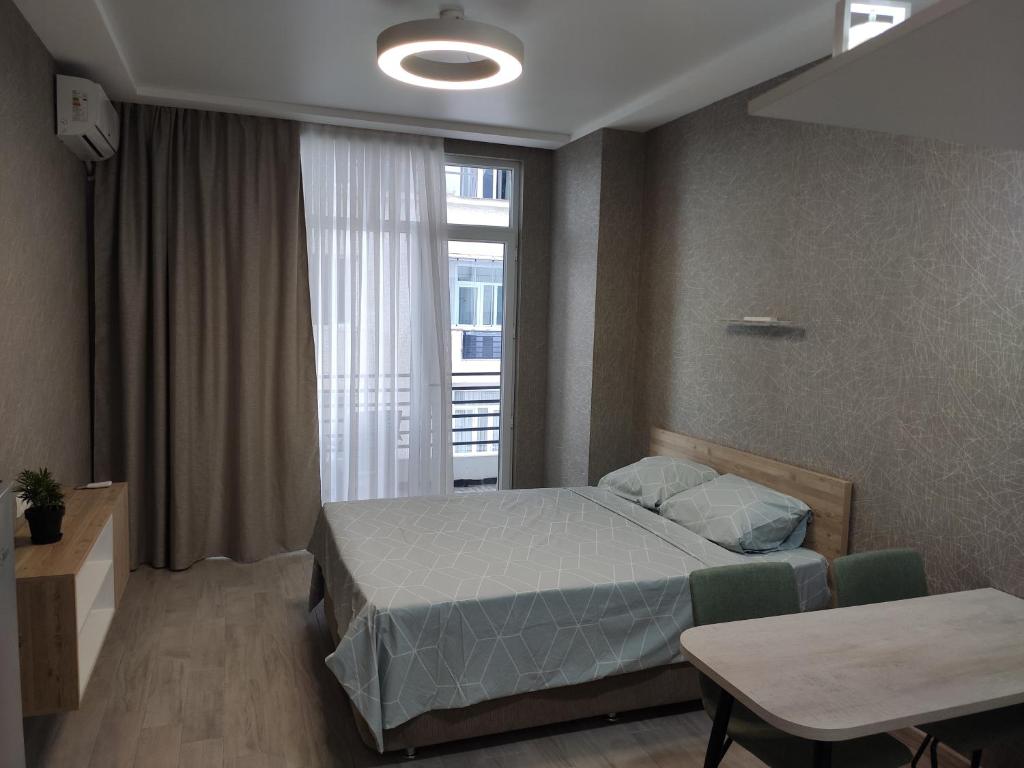 um quarto com uma cama, uma janela e uma mesa em Real Palace Studio em Batumi