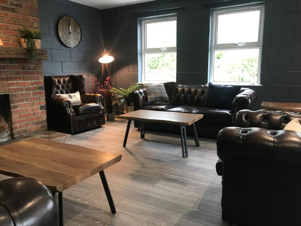 a living room with leather furniture and a brick wall at Rostrevor Mountain Lodge "Cosy & Friendly" in Rostrevor