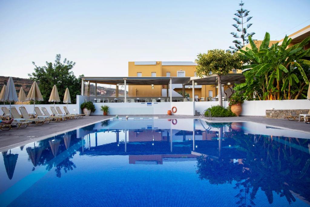 a swimming pool with chairs and a building at Xidas Garden in Bali