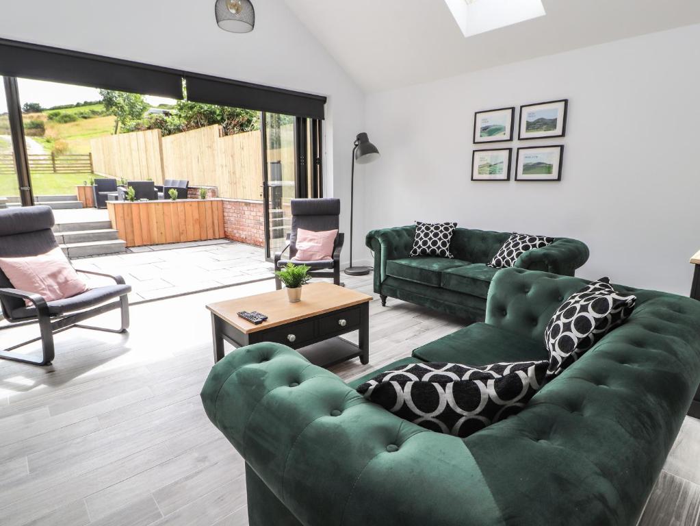a living room with two green couches and a table at Ty Coch in Ruthin