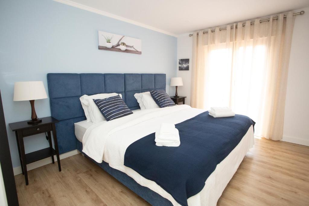 Meriteluna Pateo - Entre Lisboa, Sintra e Cascais في Agualva: غرفة نوم زرقاء وبيضاء بسرير كبير