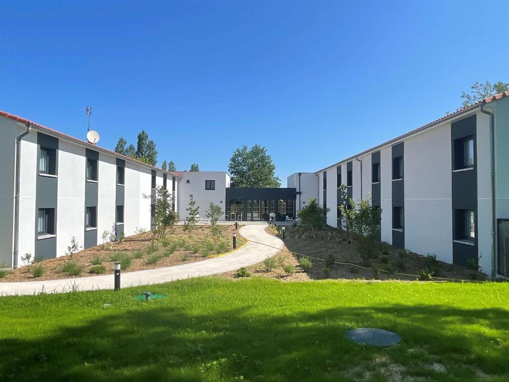 un bâtiment avec une pelouse verte devant lui dans l'établissement Sure Hotel by Best Western Les Portes de Montauban, à Montauban