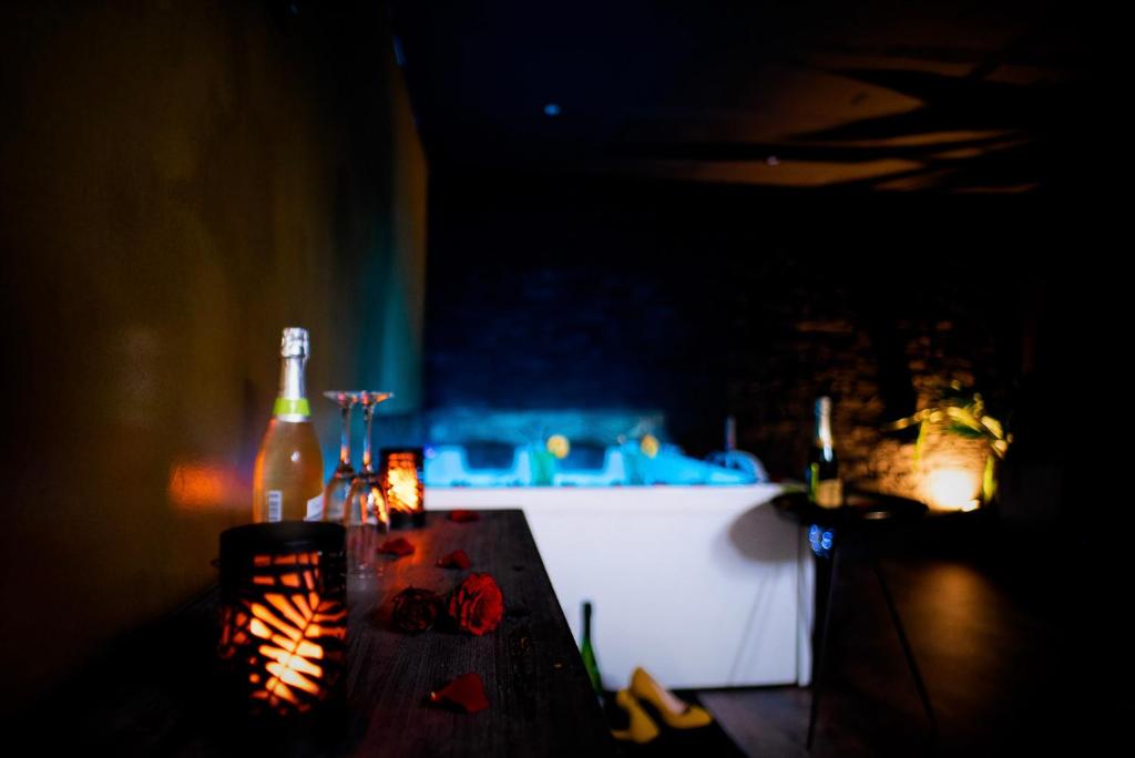 una mesa con una botella y vasos. en LOVE Suites & SPA "Le Loft" avec Jacuzzi privatif, en Médis