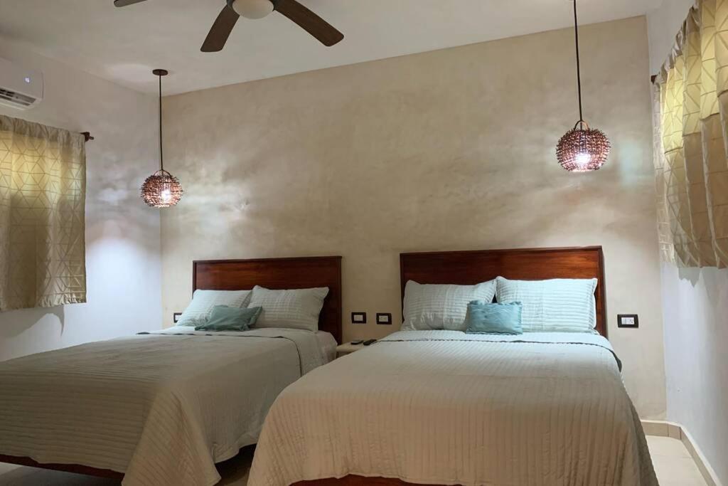 1 dormitorio con 2 camas y 2 luces colgantes en Baona Bacalar en Bacalar