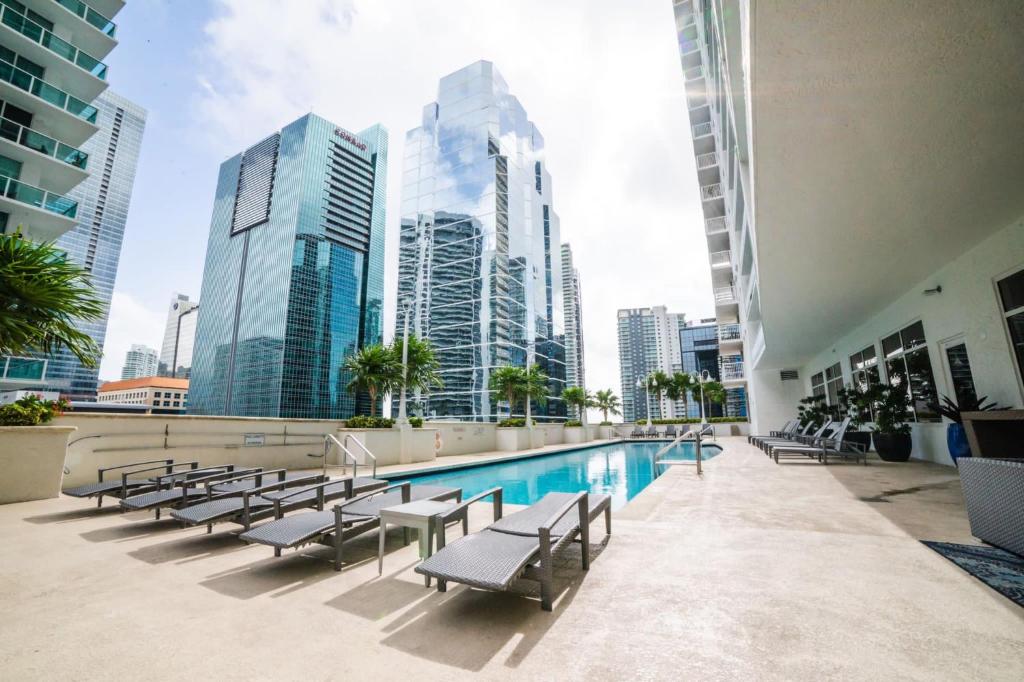 una piscina con sillas y edificios en el fondo en High Rise Brickell Modern Studio, en Miami