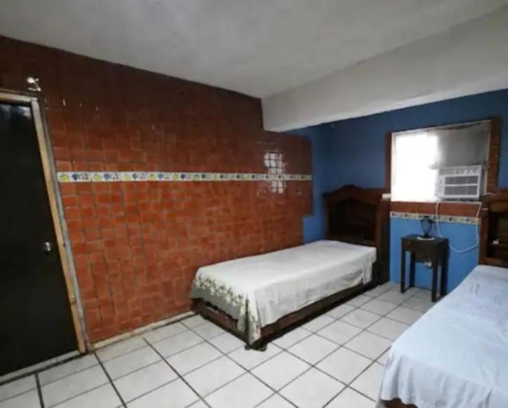 a bedroom with two beds and a brick wall at Habitación completa a 2 Cuadras del Consulado EUA in Nuevo Laredo