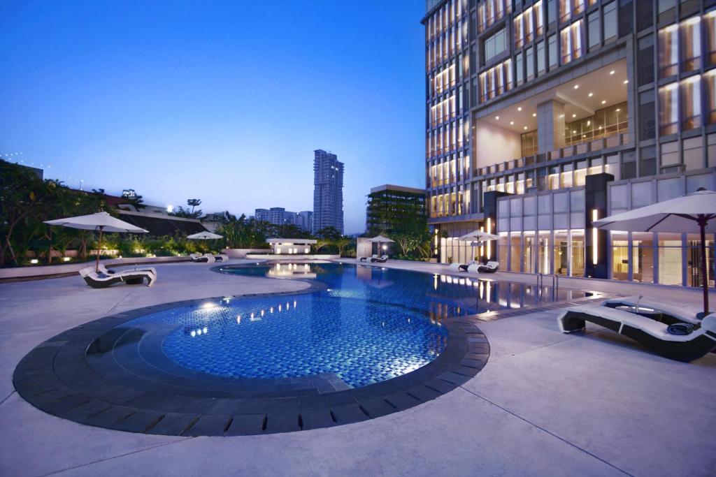 a large swimming pool in front of a building at The Grove Suites by GRAND ASTON in Jakarta