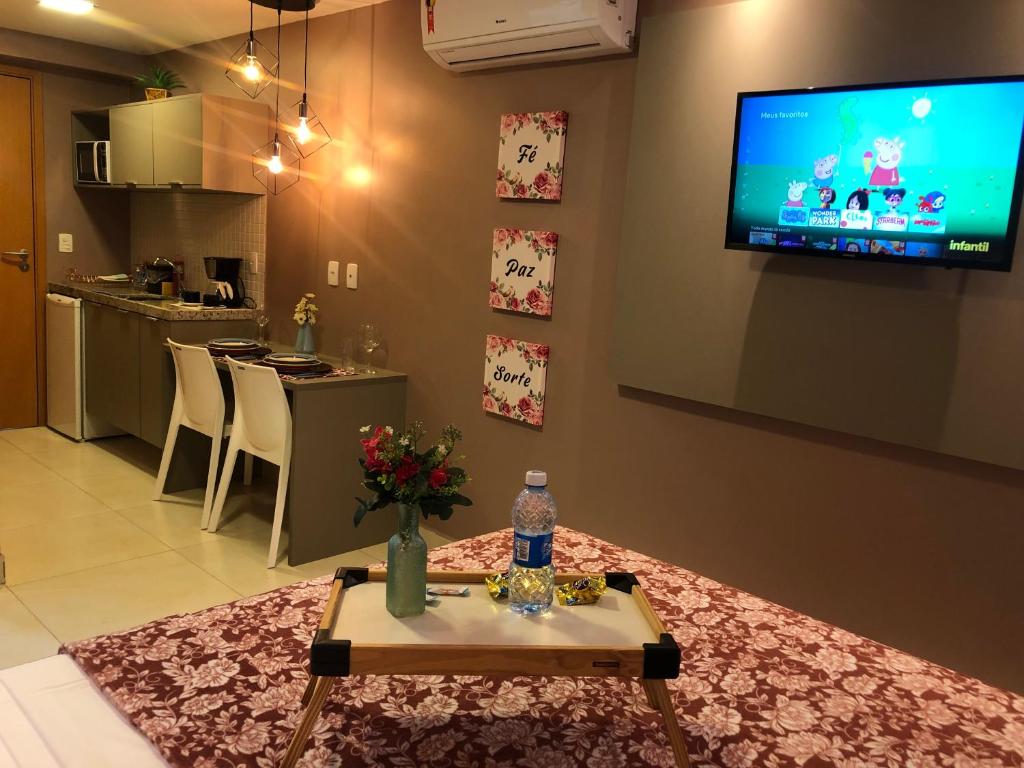 uma sala de estar com uma mesa e uma televisão na parede em Manaíra Apart Hotel - Flat 201 em João Pessoa