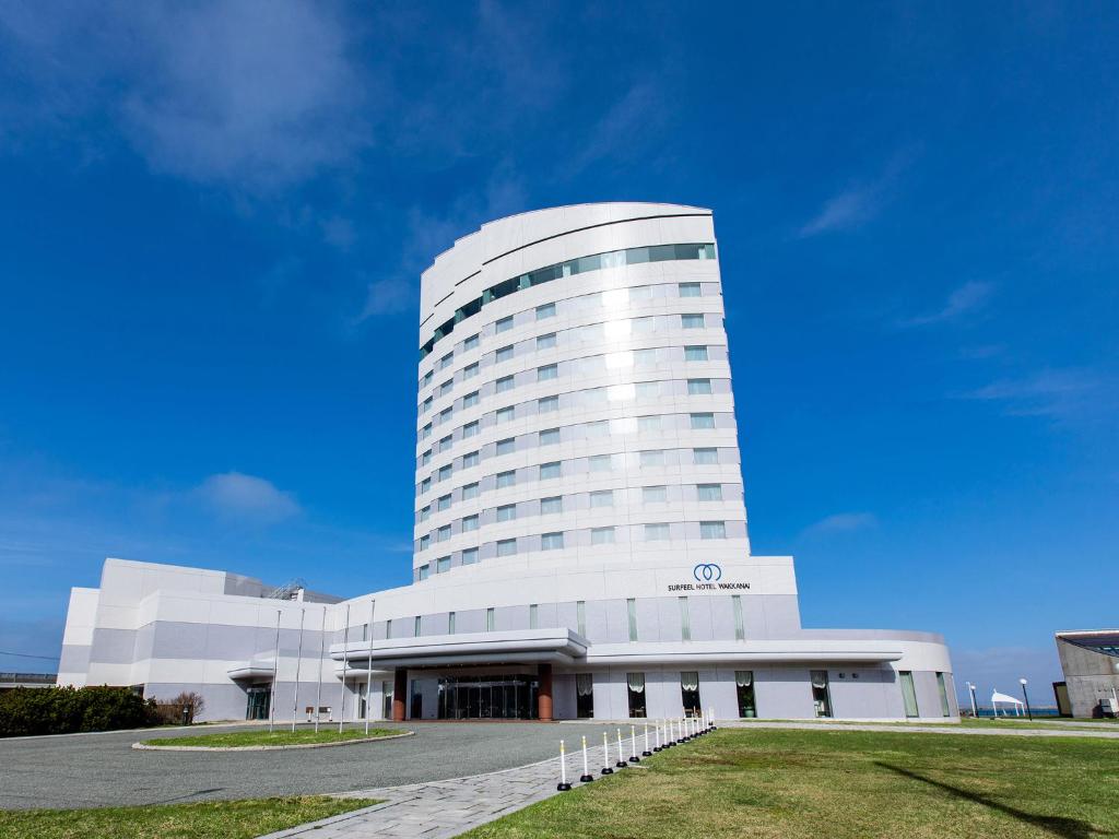 a large white building with a grass field in front of it at Surfeel Hotel Wakkanai in Wakkanai