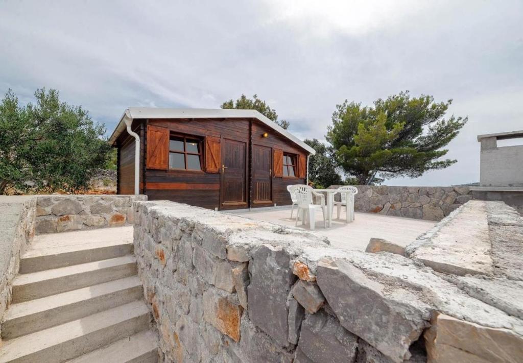 uma pequena cabana de madeira atrás de uma parede de pedra em Holiday home Dusko - robinson em Žirje