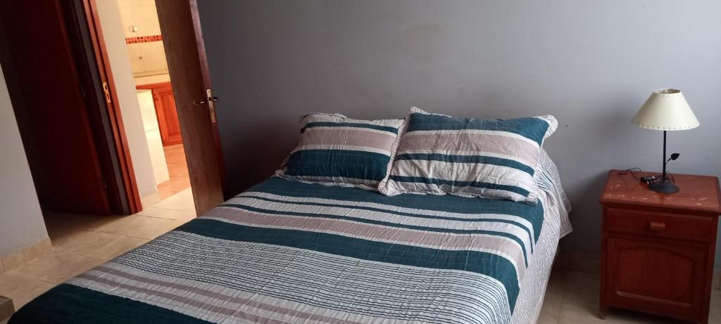 uma cama com lençóis listrados azul e branco e um candeeiro em La Hiedra em San Salvador de Jujuy