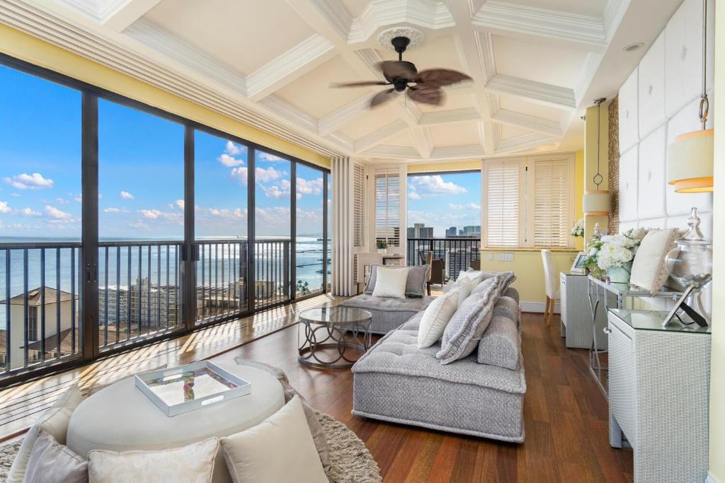 een woonkamer met een plafondventilator en grote ramen bij Oceanview Penthouse Suite in Honolulu
