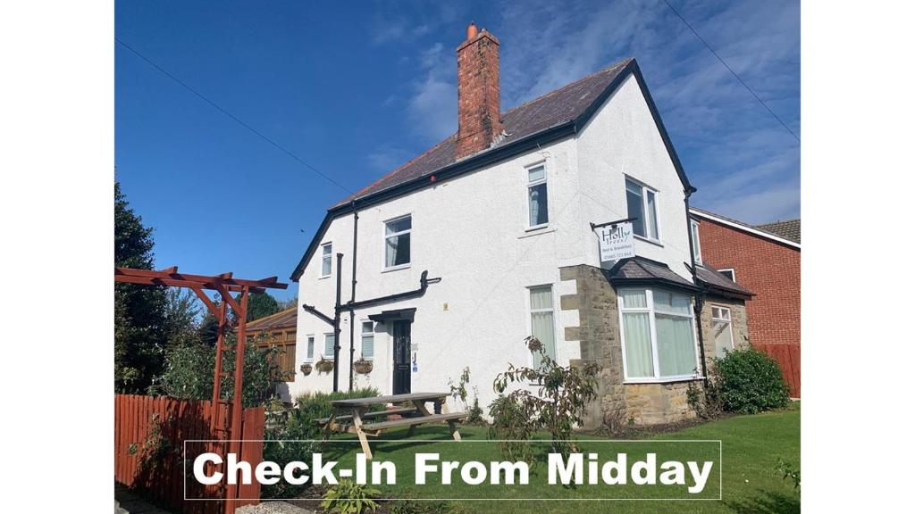 uma casa branca com as palavras check-in de Middlebury em Holly Trees em Seahouses