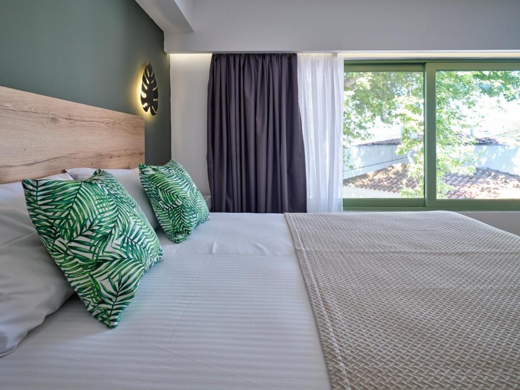 a bedroom with a bed with pillows and a window at The Tree Suites in Skiathos