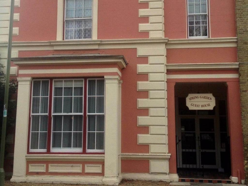 un edificio rosa con una puerta con un cartel. en Spring Garden Guest House, en Gosport