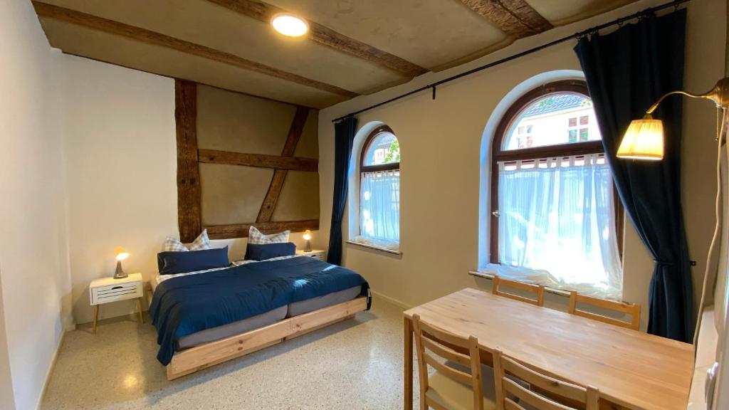 a bedroom with a bed and a table and two windows at Blaue Perle Templin in Templin